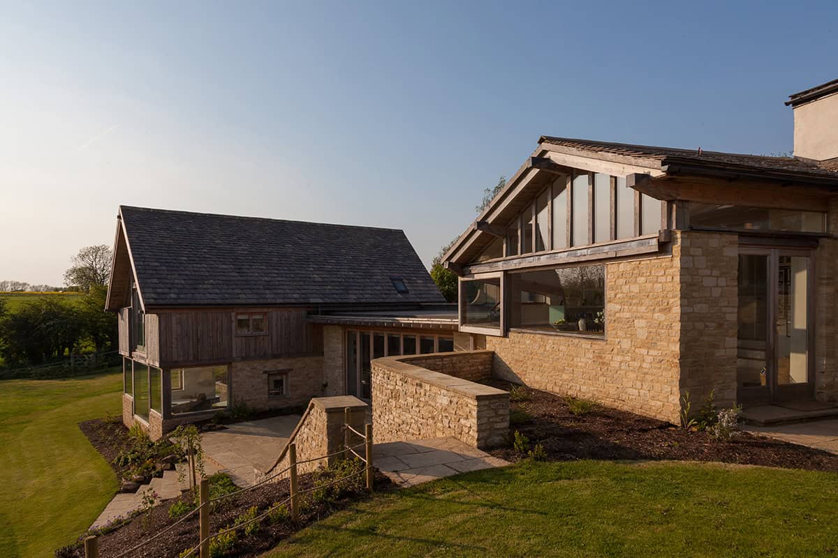 Cockadilly stone and timber extension with oak-framed glazing linked to original Cotswold house