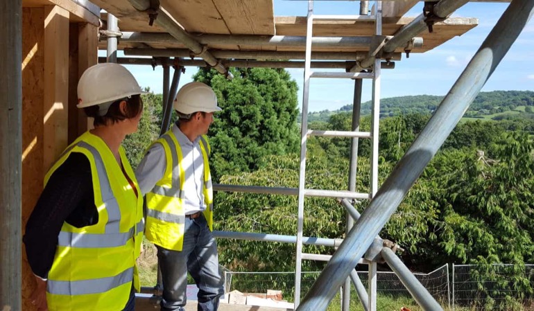 Architects on scaffolding surveying a hillside building site in the Cotswolds